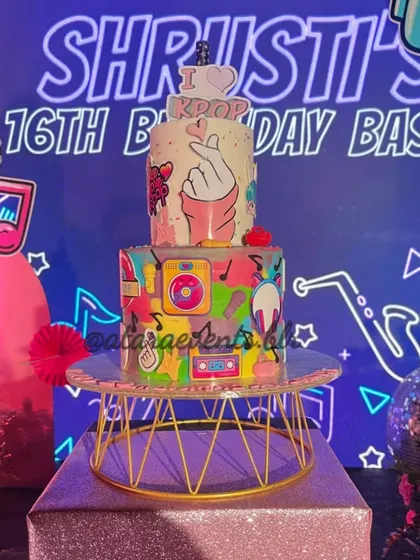 A detailed shot of the K-Pop themed birthday cake. The cake is covered in colorful icons like music notes, cassette tapes, and hearts, perfectly capturing the vibrant energy of K-Pop.
