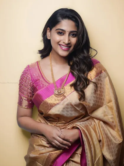 A bright and happy portrait. The yellow background complements the pink and gold saree, creating a cheerful and vibrant image.
