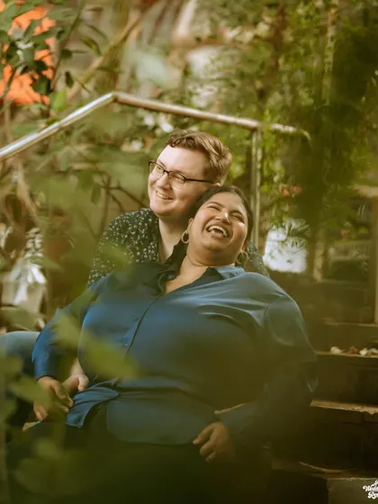 A joyful, candid moment of laughter shared between a couple on a staircase, showing their easy and natural chemistry.