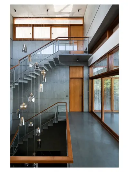 A cluster of pendant lights cascades through the stairwell, adding a touch of delicate artistry to the raw, architectural space.