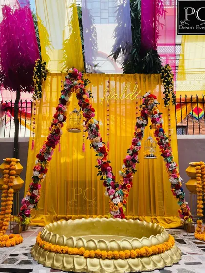 Another angle of the 'M' shaped Haldi arch, showing the colorful drapes in the background that add to the festive look.