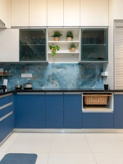 A full view of the L-shaped blue kitchen, showcasing its vibrant color, ample storage, and modern silver-profile handles.