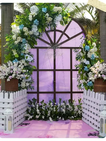 A charming photo corner with a rustic window frame, white picket fences, and blue and white floral arrangements. The "Better Together" neon sign adds a modern, romantic touch.