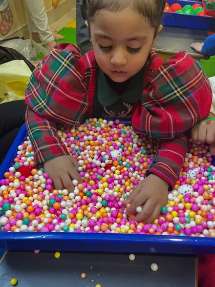 A child explores a sensory bin filled with colorful beads, a calming and engaging activity during our Christmas workshop.