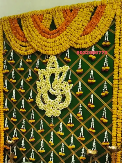 For a more traditional feel, I created this backdrop using a green lattice panel decorated with marigold garlands and a central Ganesha motif made entirely of white and yellow flowers.