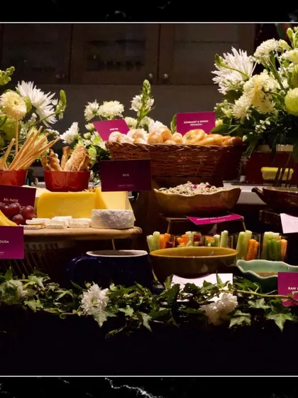 A detailed shot of a grazing table, featuring various dips, cheeses, breads, and vegetable sticks.
