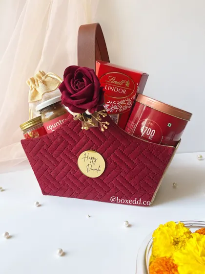 This is one of my signature Diwali hampers. I love combining rich textures and a festive color palette, like this quilted maroon basket, filled with gourmet treats and luxury items to make the celebration feel extra special.