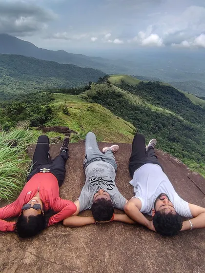 Taking a moment to relax and lie back on a rock at the summit, enjoying the view of the endless green hills of the Kudremukha range.