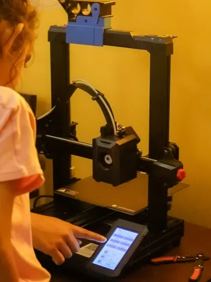 Another shot of a student operating a 3D printer. They learn to navigate the interface and monitor the printing process, gaining a comprehensive understanding of the technology.