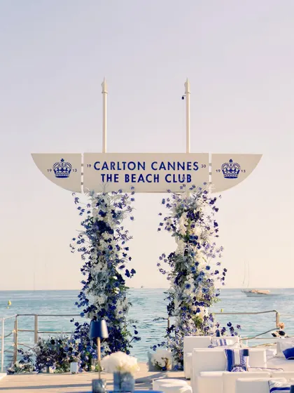 The floral entrance arch stands proudly against the iconic Carlton Cannes sign, creating a picture-perfect welcome for the guests.