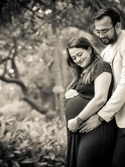 A beautiful black and white photo that captures a quiet, intimate moment. The focus is on the couple's connection and the gentle way they cradle the baby bump.