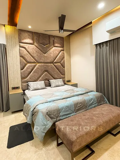 Another angle of the bedroom with the geometric headboard, showing how the design is complemented by the warm cove lighting in the false ceiling.