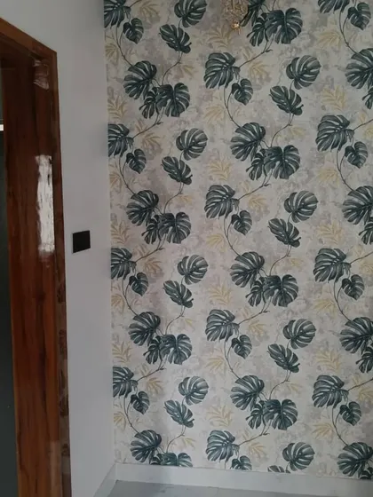 A classic monstera leaf wallpaper pattern. The design is clean and modern, adding a popular botanical touch to this wall space next to a doorway.