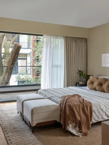 Bringing the outdoors in is a huge part of our design philosophy. This bedroom features large windows that frame the beautiful green trees outside, creating a peaceful and natural ambiance.