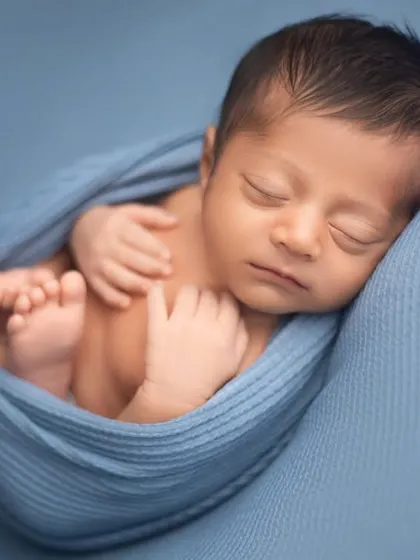 A classic womb-like pose, with the baby snugly wrapped in blue. This pose is very comforting for newborns and results in beautifully peaceful portraits.