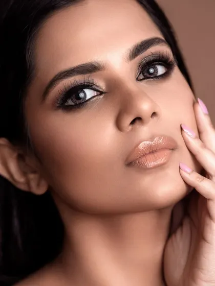 A close-up beauty portrait with a focus on glossy lips and smoky eyes. The lighting is crafted to create a soft, flawless skin texture, showcasing the result of professional retouching.