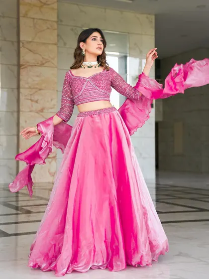 A gorgeous rose pink lehenga with a stone-encrusted blouse and dramatic ruffled bell sleeves. This is a fun, fashionable, and vibrant choice for a mehendi or sangeet party.