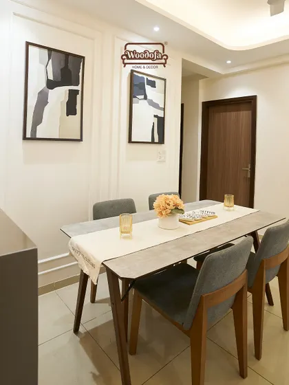 A simple and elegant dining area with a four-seater table and abstract art on the wall. The wall moulding adds a touch of classic detail.