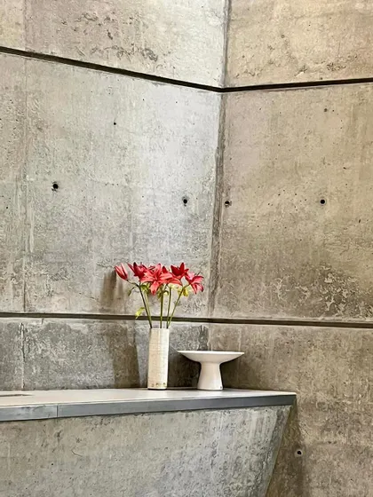 A simple moment in the 'House of Stories', where a vase of flowers sits on a concrete ledge. We believe that true luxury is found in this kind of quiet comfort, where the honesty of the materials provides a serene backdrop for everyday life.
