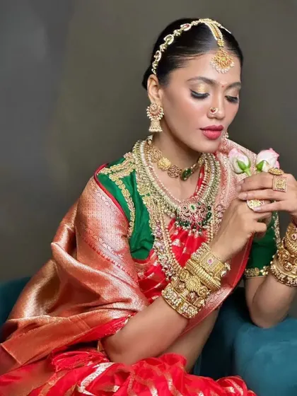 A close-up of a classic bridal updo, adorned with a delicate maang tikka. The hair is styled to perfectly frame the face and hold traditional jewelry in place.