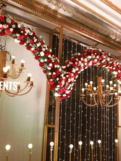 This angled shot shows the depth and detail of the red and white floral arches. This design is very popular for large wedding receptions in Bangalore and provides a stunning background for photos.