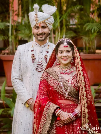 A lovely portrait of the newly married couple. The bride in her stunning red lehenga and the groom in his elegant white sherwani, smiling for the camera.