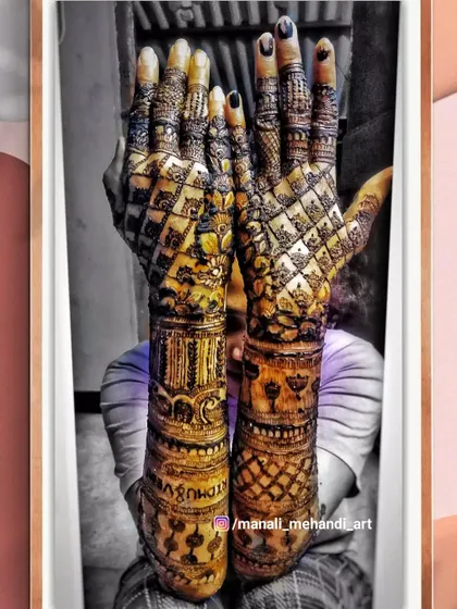 An artistic shot of a full-coverage bridal mehandi. The design is filled with dense checkerboard patterns on the back of the hands and intricate bands on the arms.