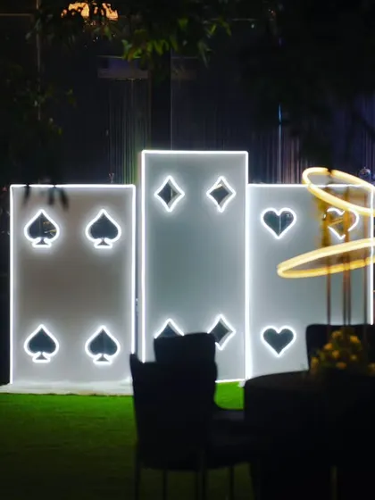 The playing card light installation seen from a distance, integrated into the overall festive ambiance of the outdoor party space.