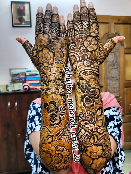 A happy client showing off her full-arm bridal mehndi. The design is packed with detail, from the fingertips to the elbows.