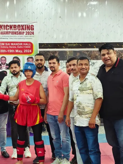 A female student stands with officials after winning her kickboxing match.