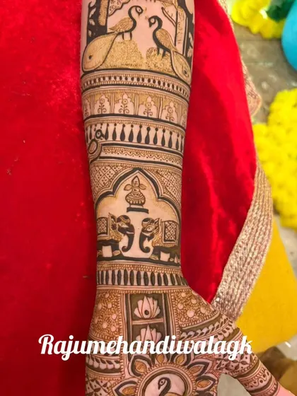 A close-up of an arm design with elephants and peacocks, showing the intricate patterns.