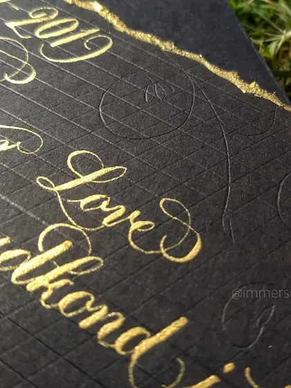 A macro shot showing the texture of the paper and the shimmer of the gold ink. You can also see the subtle, hand-pressed floral patterns in the background.