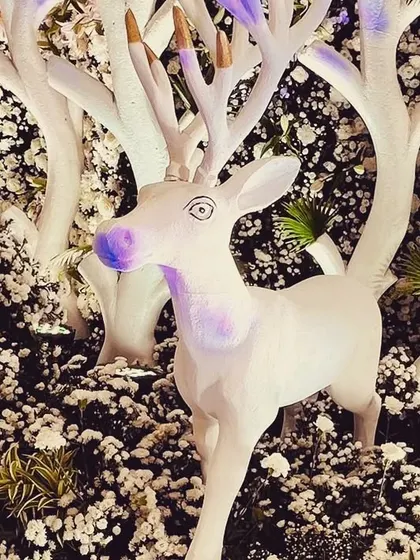 A stylized white deer prop stands amidst a backdrop of flowers, adding a whimsical touch to the forest theme. We use custom props to enhance our decorative concepts.