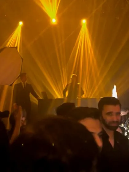 The lighting rig creates a spectacular canopy of golden beams over the dance floor. This image captures the grand production and unforgettable atmosphere of a luxury wedding party.