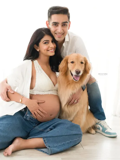 The whole family, fur baby included, comes together for this happy maternity portrait. It's a warm, genuine moment of love and excitement.