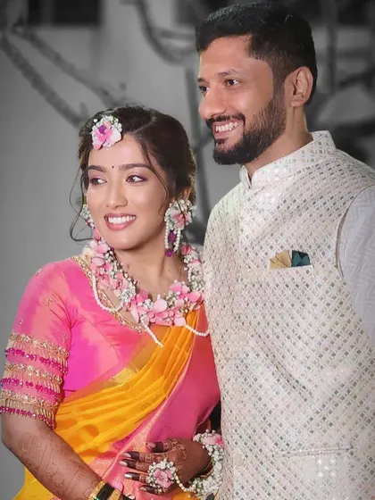 Another shot of this beautiful couple. The bride's pink floral necklace and maang tikka perfectly match her bright pink and yellow saree.