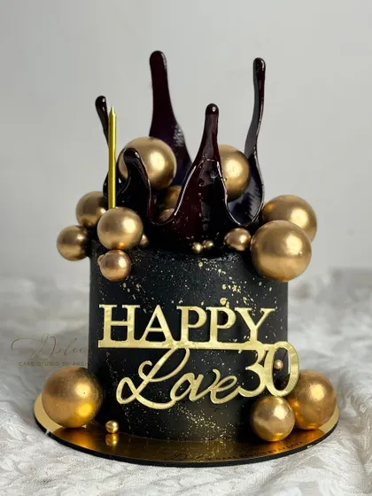 Celebrate a milestone 30th birthday with this stunning black and gold cake. It features a dark chocolate splash and a cascade of golden chocolate spheres.