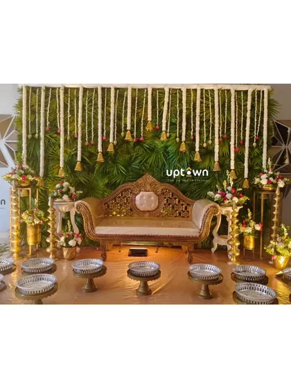 A traditional stage with a green backdrop and hanging floral strings.