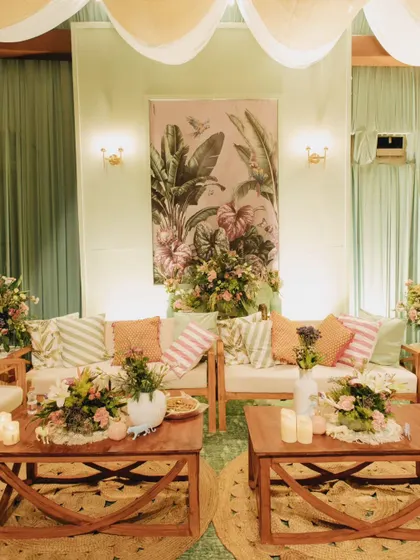 A cozy seating lounge from the tropical soiree, combining mint green and brown tones with rattan furniture, tropical print cushions, and lush floral arrangements to create a relaxed yet stylish atmosphere.