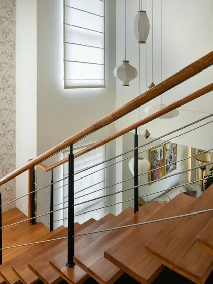 The double-height space above the staircase is accentuated by beautiful pendant lights and delicate wallpaper.