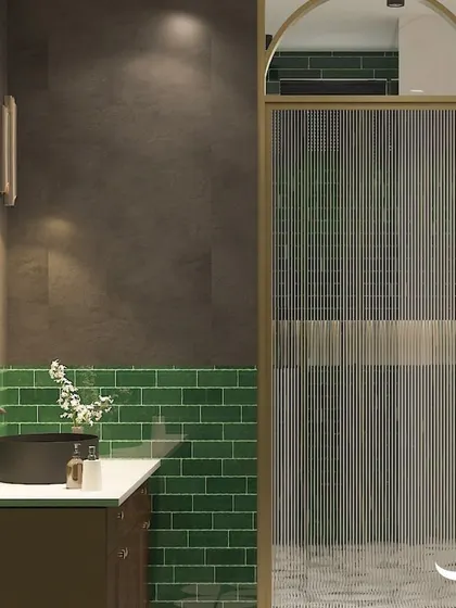 A closer look at the bathroom for Rasika in Pune, highlighting the fluted glass shower door and the rich green subway tiles.
