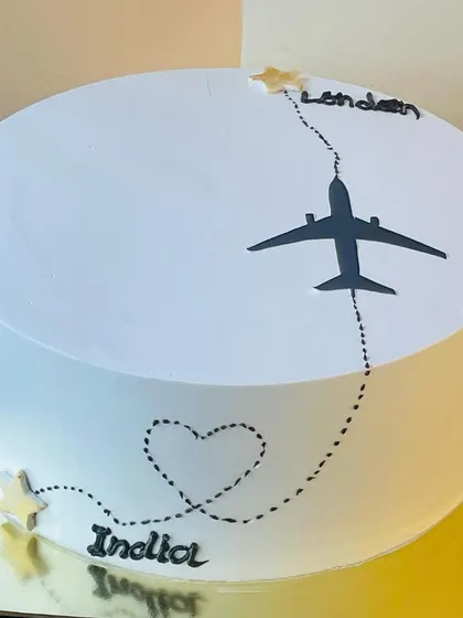 A closer view of the bon voyage cake, highlighting the clean design and the heart-shaped flight path.