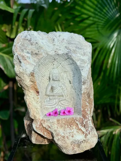 A meditating Buddha carved into a natural rock niche, blending the raw texture of the boulder with the refined art of sculpture.