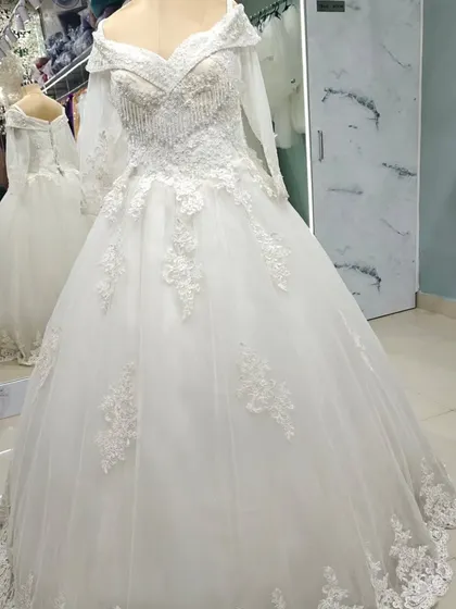 A full-length view of the off-the-shoulder embroidered ball gown. The floral lace appliqués cascade from the bodice down onto the voluminous tulle skirt.