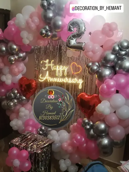 A vibrant 2nd-anniversary decoration. The ring is decorated with pink, white, and silver balloons, a neon sign, and heart-shaped foil balloons, making it a lovely setup for a couple's celebration at home.