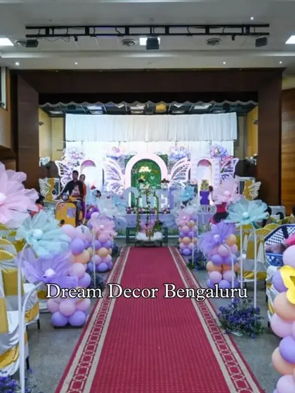 A wide shot of the butterfly-themed party hall, showing the aisle decor leading up to the main stage.