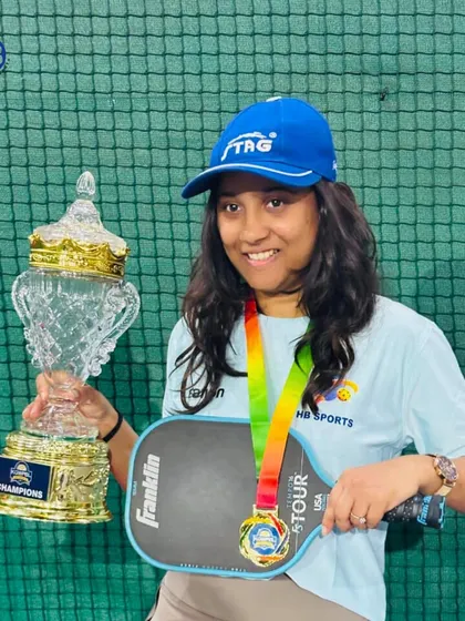 A female pickleball champion holds her trophy and medal. We celebrate the power and success of women in sports and are proud to provide a platform for them to excel.