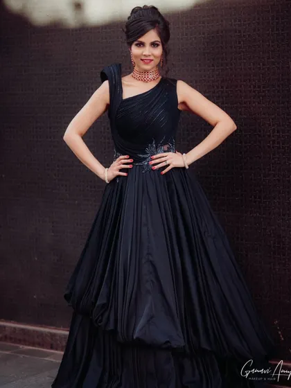 A full-length portrait of a stunning reception look. The bride's elegant black gown is paired with a sophisticated updo and bold makeup.