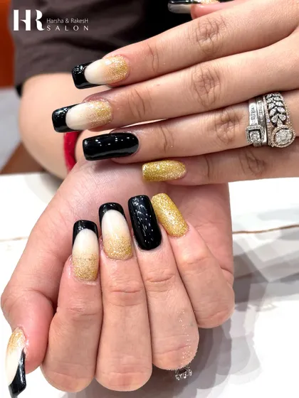 A glamorous combination of black and gold. This design features a mix of solid glossy black, sparkling gold glitter, and a modern French tip with a glittery nude base.