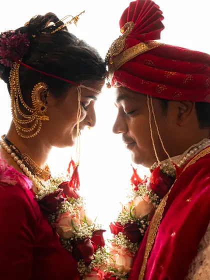 A beautifully backlit silhouette shot of a couple in their Maharashtrian wedding attire, creating a dramatic and artistic portrait.